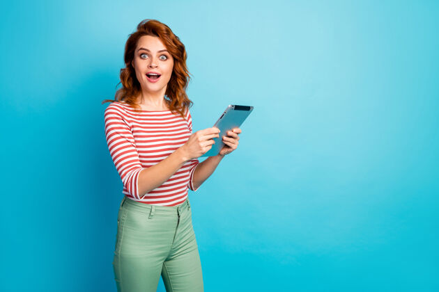 网络激动可爱可爱的可爱女孩的肖像使用平板电脑搜索难以置信的信息印象深刻尖叫哇omg穿好看的衬衫隔离蓝色惊喜时髦新闻
