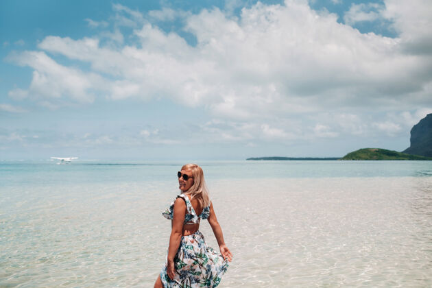 海滩一个穿着泳衣的女孩站在海洋中 在毛里求斯岛上的莫恩山的背景下等待一架水上飞机旅游山白天