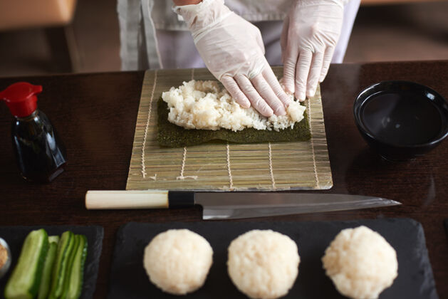 餐制作卷寿司过程的特写镜头诺丽和白米厨师的女性手触摸米饭厨师开始做寿司健康竹席厨师