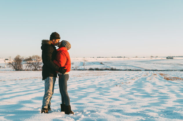 活跃一对热恋中的情侣穿着暖和的衣服 在雪域冬日的乡间拥抱亲吻自然纽带约会