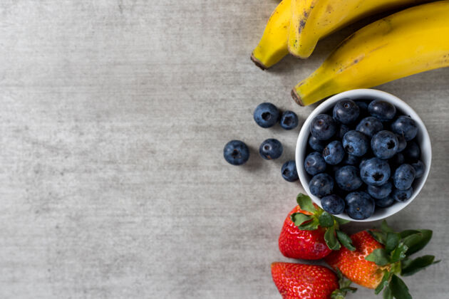 彩虹背景是放在木桌上的新鲜健康水果香蕉 蓝莓和草莓顶视图复制空间美味多汁五颜六色