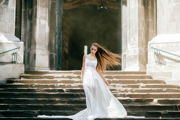 古代年轻优雅的女孩 一头飘逸的白发 身着白色长裙 在古宫殿的楼梯上摆着姿势楼梯石头模型
