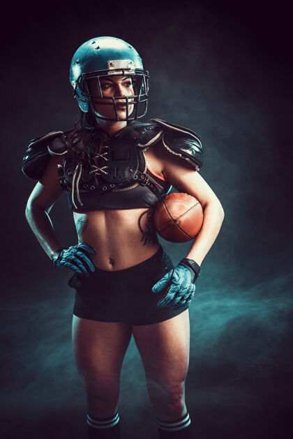 女孩穿着性感制服的年轻黑发橄榄球运动员与球合影坐着运动蹲