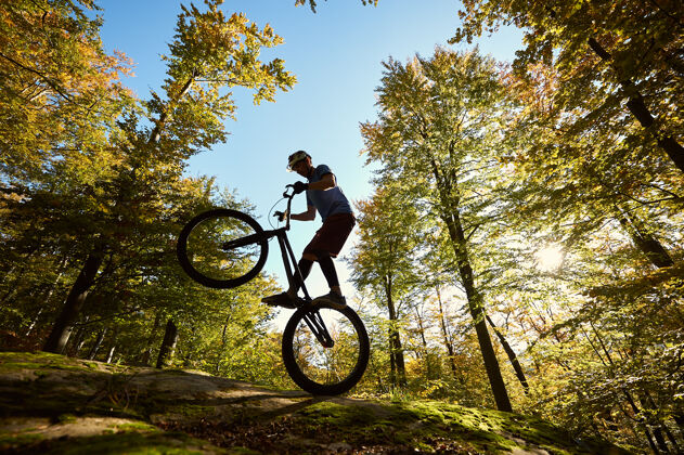 平衡在日落时分 职业自行车手在试骑自行车上保持平衡试验山轮廓