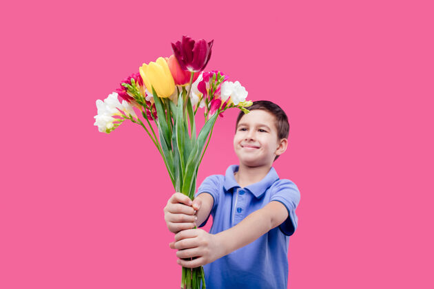 小快乐的小男孩展示郁金香花束 隔离在粉红色的墙上男孩小郁金香