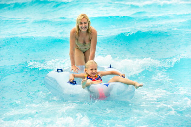 戒指一个女人带着一个孩子在一个橡胶充气圈里 在一个夏日水上公园的水池里冒雨玩耍床垫家庭游泳池