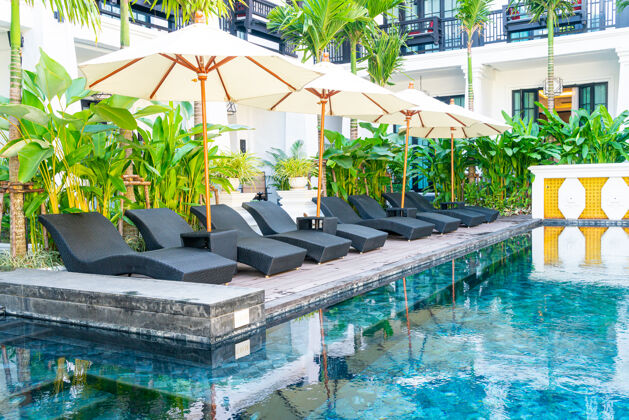 海洋伞和床游泳池周围的椅子游泳池-度假和旅游度假的概念天空休闲棕榈