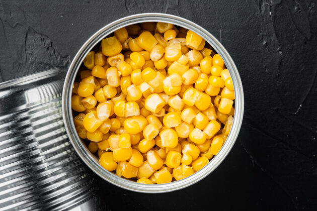 食物甜玉米粒在铁皮罐里 放在黑桌子上 俯视平躺甜玉米顶视图种子