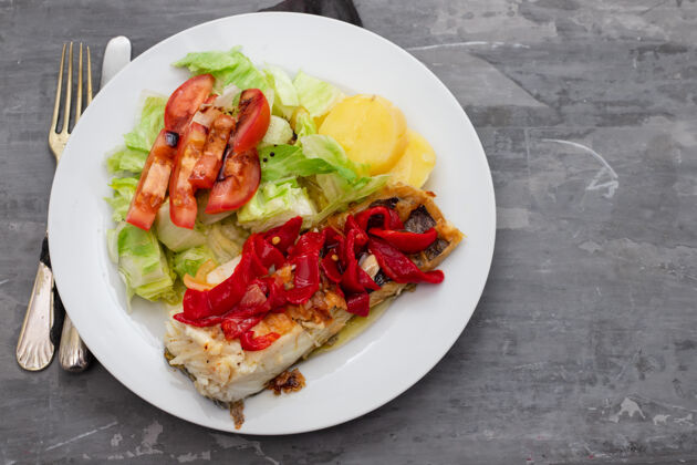 香草红椒鳕鱼 土豆和沙拉放在陶瓷背景的白色盘子里餐厅鱼海鲜