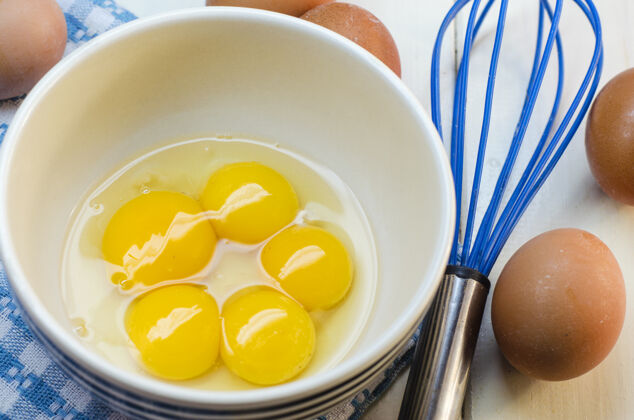 蛋黄生鸡蛋和花冠在白色的表面食物配料早餐