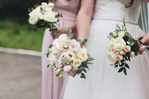 花束身着白色礼服的新娘与伴娘手持结婚花束牡丹玫瑰复古