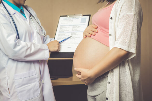 婴儿快乐的孕妇到医院或诊所找妇科医生做妊娠顾问年轻人产妇腹部