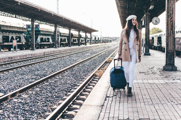 货车一个身穿贝雷帽和米色夹克的女人带着手提箱穿过火车站的画像女孩女性大厅