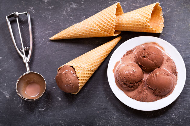 奶制品一盘巧克力冰激凌勺和华夫饼蛋筒在深色背景上甜点蛋卷勺子