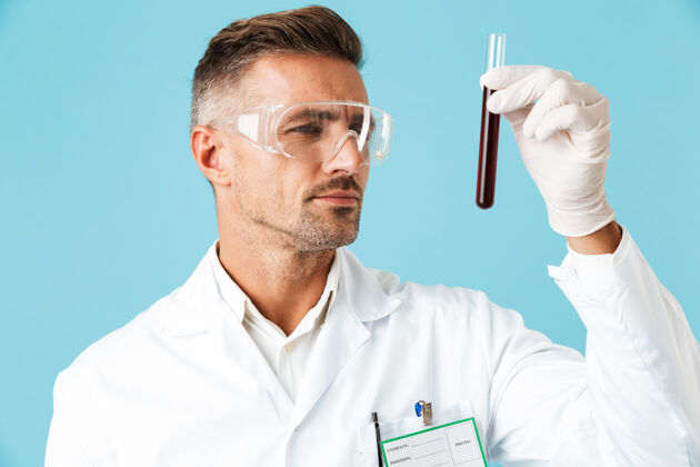 血液成熟的医学专家戴着眼镜拿着带血的试管 孤零零地站在蓝色的墙上外套管成人