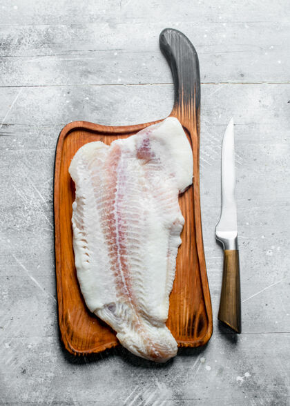 配料鱼片放在木砧板上刀开白色质朴的桌子板鱼片去骨