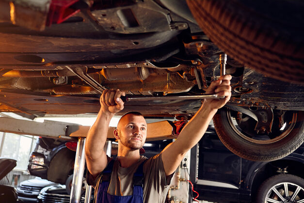 人员帅气的汽车修理工在加油站检查汽车的传动装置站技术过滤器