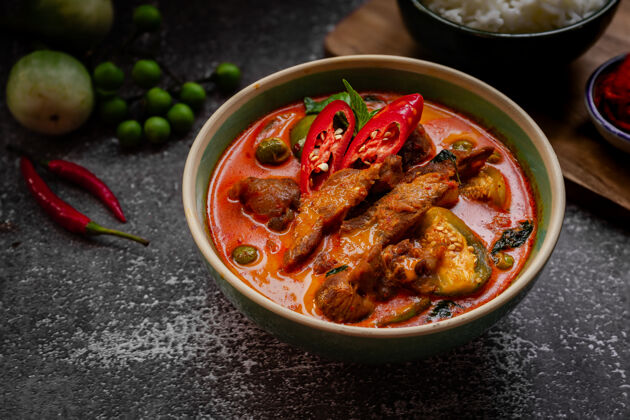 酱泰国菜-黑桌子上的辣味猪肉红咖喱咖喱酱亚洲菜传统菜