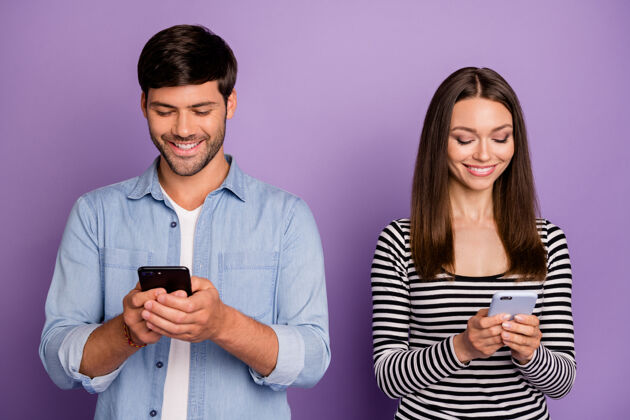电话两人情侣男女士拿着电话数喜欢粉丝转发分享上瘾社交网络用户穿休闲装隔离紫色墙年轻手机在线