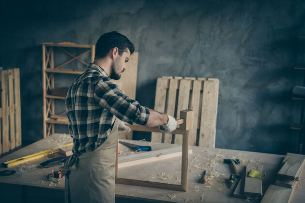 房子后视图严肃自信的男子用锤子完成木架定做修复生产围裙