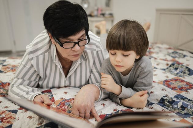 女人外婆和外孙在家一起看书的正面图女性祖母祖父母