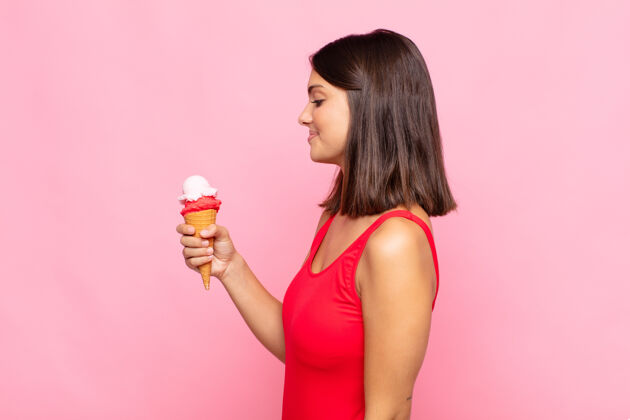 女性拿着冰淇淋的年轻漂亮女人锥形夏季董事会墙壁勺子时尚