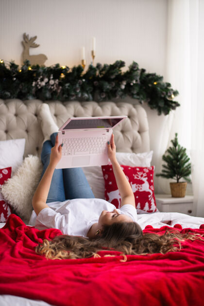 圣诞节女孩在网上工作 从家里 躺在床上 视频链接舒适室内美丽