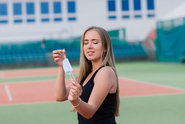 健康女网球手戴着防护面具在球场上打球隔离美丽球