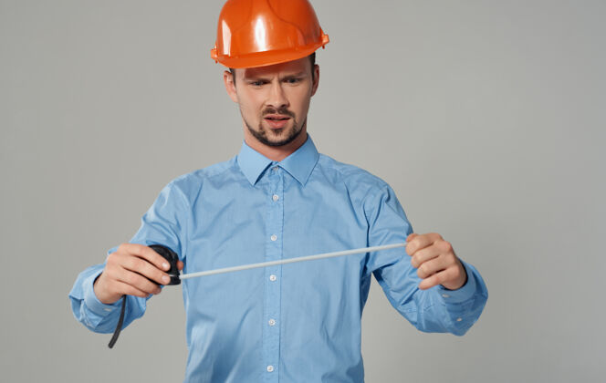 年轻人男建筑工人手里拿着卷尺就一个灰色的男人工头勤杂工