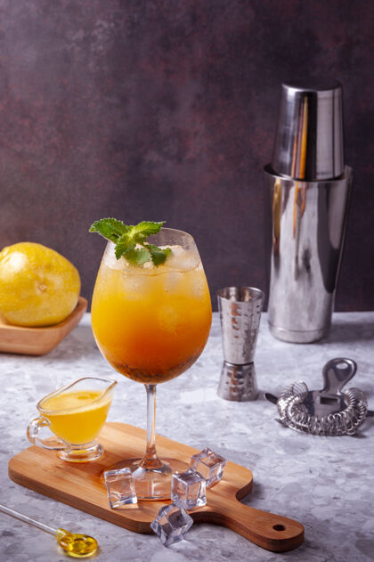 冰西番莲果鸡尾酒放在厨房板上 地板上放一些冰块 整个西番莲果 鸡尾酒摇壶 滤网和剂量计副本空间柑橘鸡尾酒饮料