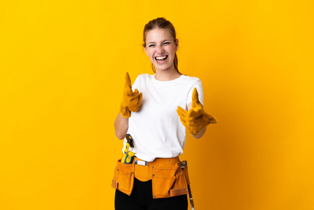 木匠被隔离在黄色背景上的女电工指着前面微笑着表情指工匠