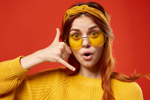 快乐开朗感性的戴眼镜的女人黄色毛衣特写红墙时髦嬉皮士波西米亚