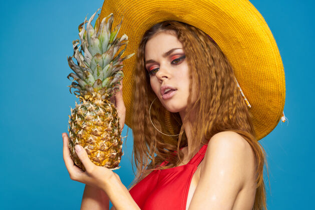帽子戴着黄色帽子的女人 手里拿着菠萝 心情愉悦 生活方式 夏日水果蓝墙季节模特鸡尾酒