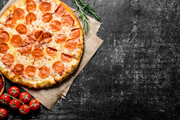 奶酪香喷喷的意大利香肠披萨在纸上放在深色的木桌上火腿圆形传统