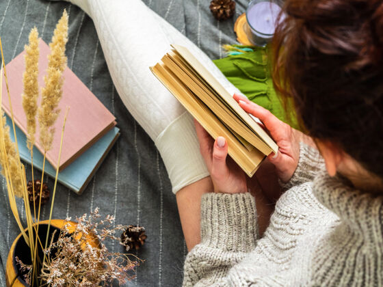 自然女孩拿着一本书一个穿着针织毛衣的女孩被许多书包围着毛衣冬天放松