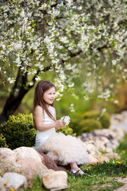 快乐美丽微笑的小女孩 穿着奶油色的裙子 在花圃里田野看花
