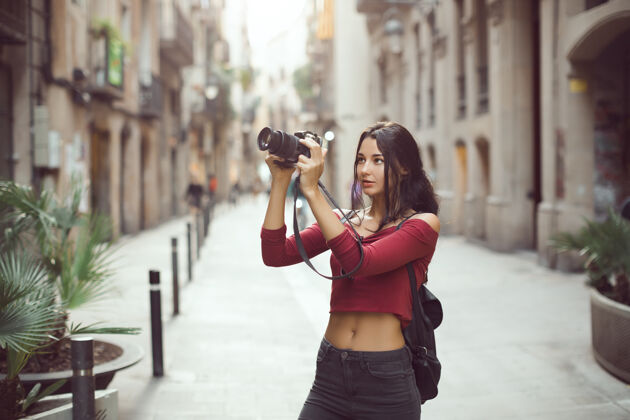 旅游迷人的旅游女摄影师拍摄的单反相机在户外的城市街道上户外女人专业