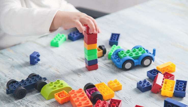 发展小女孩在玩五颜六色的建筑塑料块兴趣房子游戏