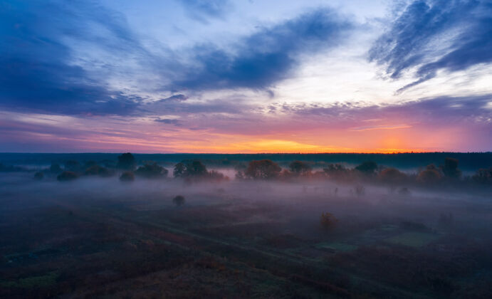 地标日出时的晨曦 雾气弥漫在乡村田野 天空多云黄昏景色树