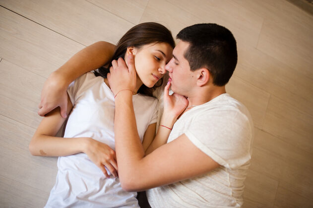 感情年轻夫妇在地板上接吻乐趣甜心女人