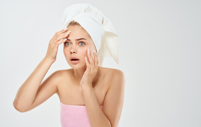 卫生一个头上戴着毛巾的女人用手在浅色背景上抚摸她的脸问题身体棕色
