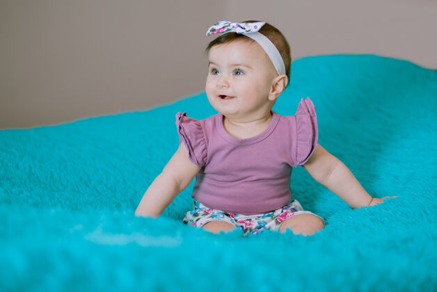 可爱快乐可爱的宝宝在床上穿着紫色的连衣裙看着妈妈休闲欢乐床