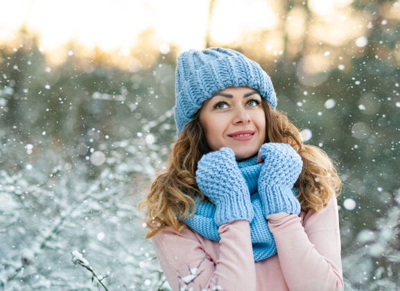 帽子冬天的肖像画 年轻漂亮的卷发黑发女子戴着蓝色针织围巾覆盖在雪上冬天的衣服户外成人
