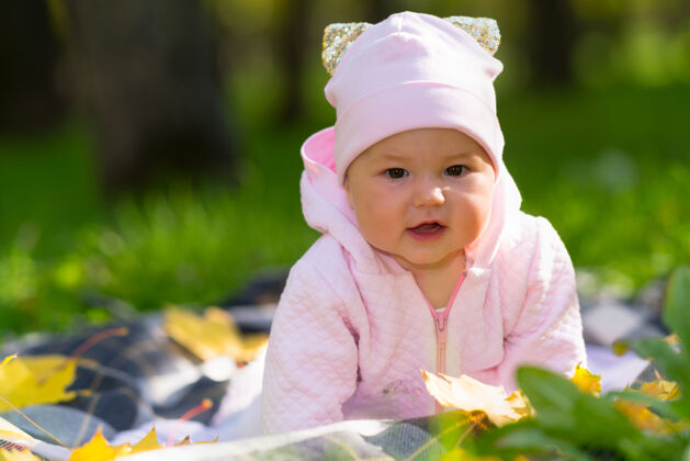 刺激在秋天的公园里 一个好奇的小女婴在铜管上的毯子上爬来爬去 看着摄像机抬起双臂毯子快乐新生儿