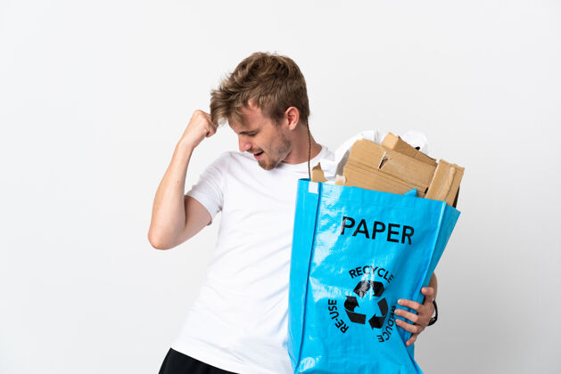 男性年轻的金发男子拿着一个装满纸的回收袋 在白色的孤岛上庆祝胜利青年青年责任