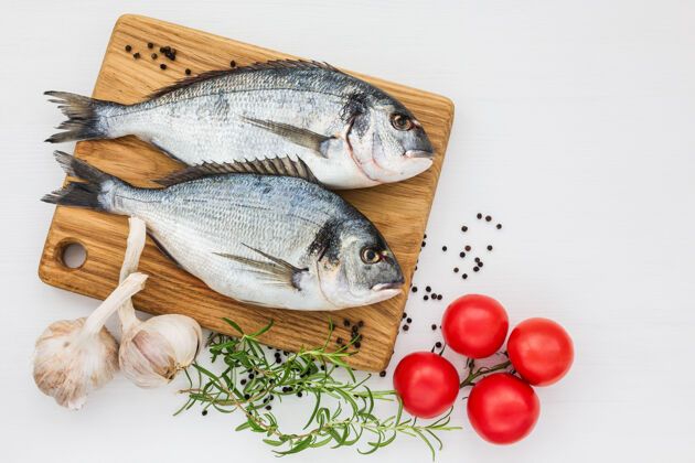 食物新鲜的多拉多鱼放在木制的切肉板上 上面放着大蒜和西红柿桌面查看 复制鲷鱼烹饪一餐