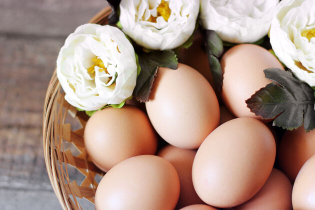 传统鸡蛋和花放在木桌上的篮子里鲜花季节早餐
