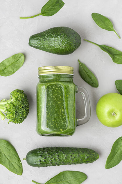 自制用菠菜 花椰菜 鳄梨 苹果和蔬菜做成的健康的绿色冰沙黄瓜上衣视图.平面生的素食概念.垂直方向水果黄瓜多汁