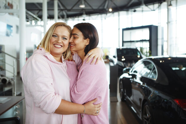 微笑一个高大漂亮的女人和一个金发胖胖的女人在一家经销店买了一辆汽车车那个买车的概念超重汽车肖像