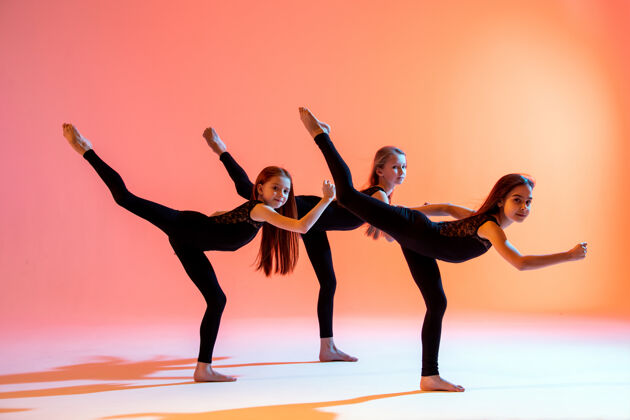 女性三个穿着黑色紧身套装的芭蕾舞女孩在红色背景下跳舞青少年红色平衡